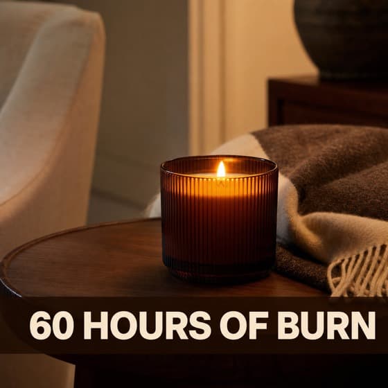 Ad creative: a lit amber candle on a side table beside a wool throw.